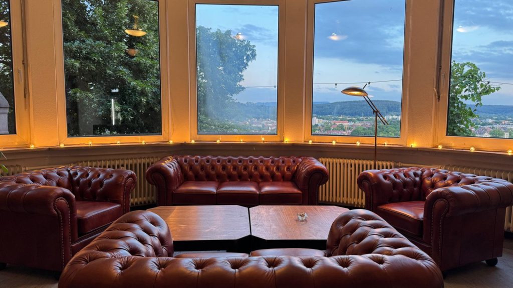 Der Clubraum mit Ledersofas vor der Fensterfront ins Tal