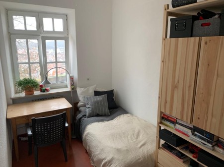 Zimmer mit Schreibtisch am Sprossenfenster und Regalwand